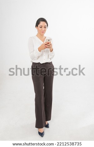 Studio portrait photo of a young beautiful elegant Brazilian female businesswoman lady wearing smart casual business attire posing with a series moments of emotion and gesture of using her smartphone Royalty-Free Stock Photo #2212538735