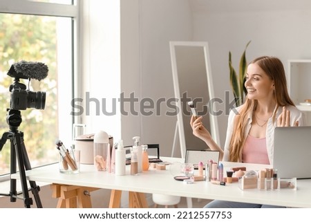 Female beauty blogger with makeup brush recording video in dressing room