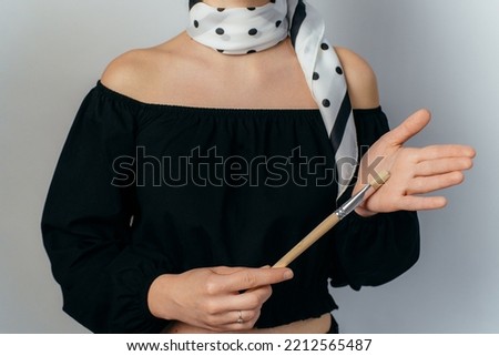 elegant woman holding a spotted painting brush on white background