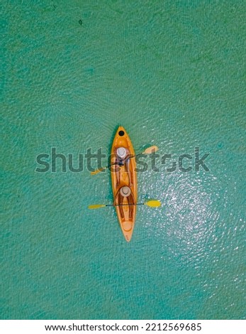 Men and women in a Kayak peddling in the turquoise-colored ocean of the tropical Island of Koh Mak Thailand. men and women in kayaks at a blue ocean and white beach with palm trees Royalty-Free Stock Photo #2212569685