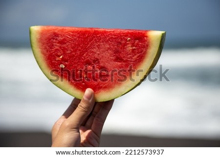 Fresh watermelon slice at the beach held in left hand a refreshing fruit for summer Royalty-Free Stock Photo #2212573937