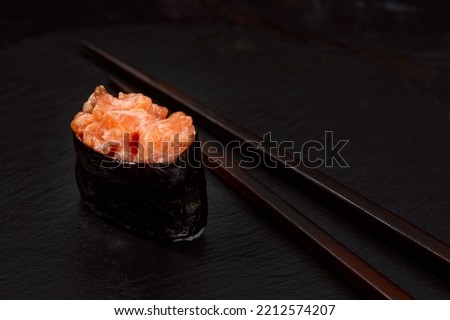 Warm rolls with tuna, salmon, perch, eel, tobiko caviar, nori, rice, cucumber on black background.