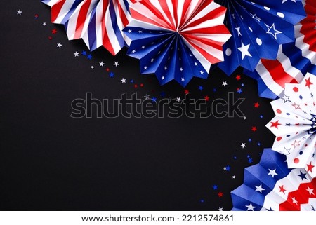 Decorations of red white and blue paper fans and confetti on black background. Veterans day, Memorial Day, 4th of July banner design.