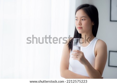 Beautiful young asian woman drinking glass of water mineral pure with fresh and happy at home, asia female drinking beverage for healthcare and weightloss, one person, lifestyles concept. Royalty-Free Stock Photo #2212575223