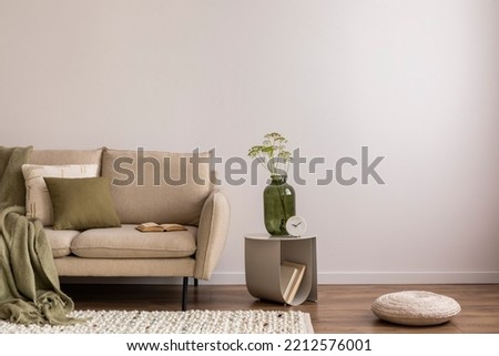 Interior design of elegant and outstanding space with copy space, beige sofa, coffee table, vase, green plaid and books. Beige wall. Minimalist home decor. Template. 