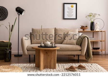 Domestic and cozy interior of living room with beige sofa, wooden shelf, pouf, furniture, green plaid, coffee table and boucle carpet. Mock up poster frame. Beige wall. Home decor. Template. 
