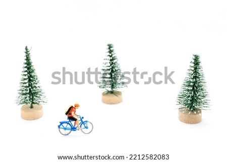 Miniature people with gifts on a bicycle, christmas tree decoration on white background