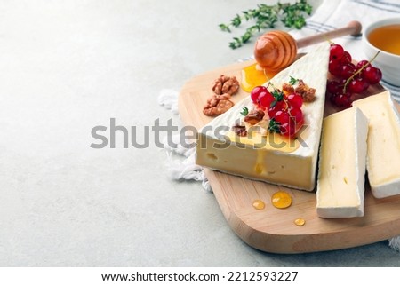 Brie cheese served with red currants, walnuts and honey on light table. Space for text Royalty-Free Stock Photo #2212593227
