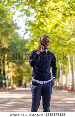 Attrctive and handsome businessman is talking on the phone while standing outside alone Royalty-Free Stock Photo #2212598125