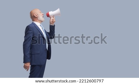 Corporate businessman shouting a message using a megaphone, marketing and communication concept, blank copy space Royalty-Free Stock Photo #2212600797
