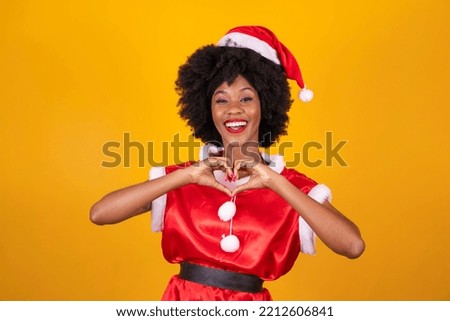 Beautiful black woman in clothes for christmas in gratitude making a heart with her hands
