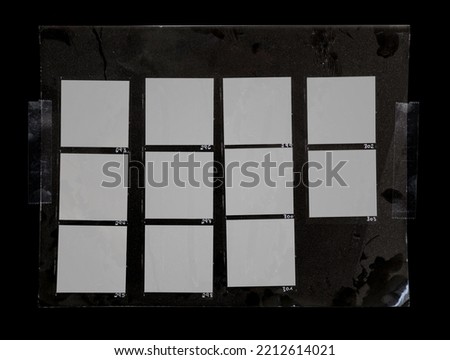 macro photo of black and white hand copy contact sheet with many empty film frames fixed by transparent sticker tape on dark background. cool photo placeholder or poster element.