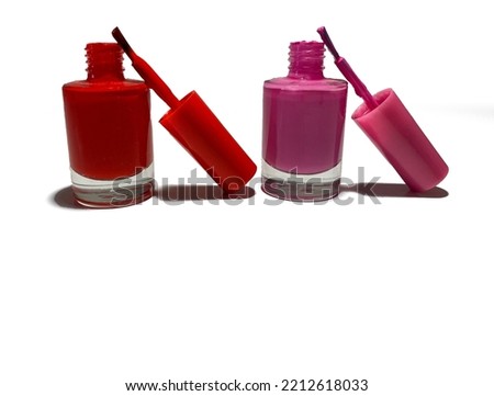 On a white background, there are two tubes of nail polish. They are open, with the brushes resting on them. The nail polishes are red and pink. Beautiful and vibrant colors.