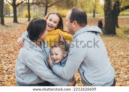 Happy joyful young family father, mother with their daughter and son having fun outdoors, playing together in autumn park. Family relation. Joint summer weekend
