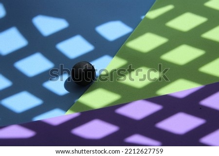 Minimalist black ball with diamond shadows and background in geometric colors.