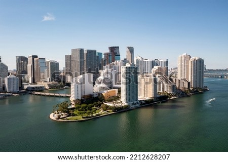 Drone shot of miami city, modern towers and buildings facing the sea, clear sky, sailing boat, bridges, tropical plants