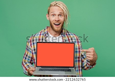 Young caucasian blond IT man with dreadlocks wear casual shirt hold use work point finger on laptop pc computer with blank screen workspace area isolated on pastel plain light green background studio
