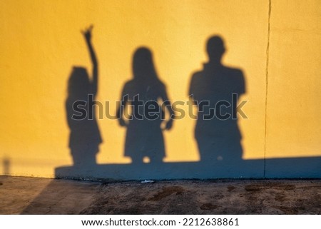 Shadows of a family of three people on the wall at sunset time. Group of human shadows on the stone wall background. Royalty-Free Stock Photo #2212638861