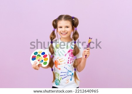 A beautiful little girl with paints and a palette in her hands, the concept of painting pictures, children's creativity and drawing.