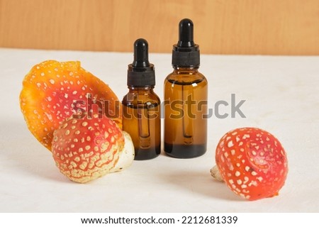 fly agaric red and amber glass dropper bottles, fly agaric extract for skin and joints treatment, fly agaric microdosing, biohacking to improve the state of the body and mind Royalty-Free Stock Photo #2212681339