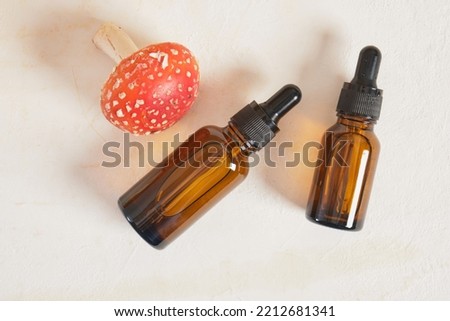 fly agaric red and amber glass dropper bottles, fly agaric extract for skin and joints treatment, fly agaric microdosing, biohacking to improve the state of the body and mind Royalty-Free Stock Photo #2212681341