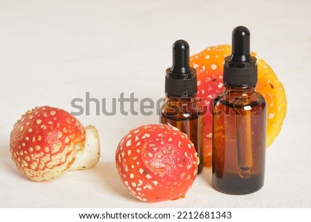 fly agaric red and amber glass dropper bottles, fly agaric extract for skin and joints treatment, fly agaric microdosing, biohacking to improve the state of the body and mind Royalty-Free Stock Photo #2212681343