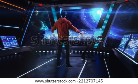 Futuristic Video Game Concept: Gamer Puts on Virtual Reality Headset and Enters Augmented Reality Action, He is Captain of the Space Ship. Cosmos Exploration Immersive Experience, Having Fun. Royalty-Free Stock Photo #2212707145
