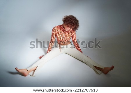 Portrait of beautiful slim young woman with short brunette hair in white trousers and red blouse in studio with white background. Girl model posing during photo shoot