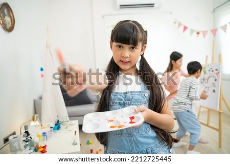 Portrait of girl artist with paintbrush in hands while holds pallete.
