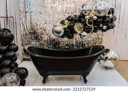 A wall with a bath for photography. A place for congratulations on birthday. Arch or photo booth decorated black and silver balloons and led strips. Zone with decor sparkling sequins for wedding.