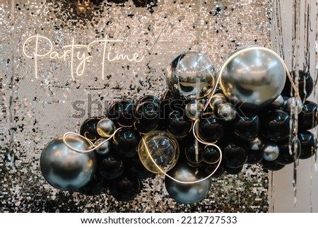 Arch or photo booth decorated black and silver balloons and led strips. Zone with decor sparkling sequins for wedding. A place for congratulations for birthday. Text party time. Happy New Year 2023.