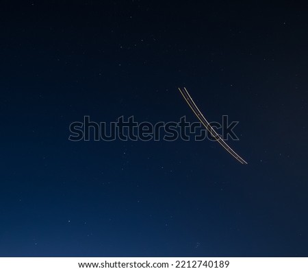 The trail from the plane at night in the starry sky at long exposure, cloudless winter night