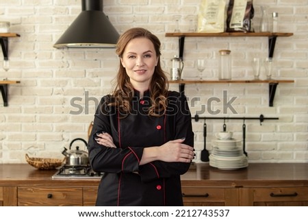 Woman in chef's uniform in the kitchen. Space for text. Professional pastry chef, chocolatier, baker or cook Royalty-Free Stock Photo #2212743537
