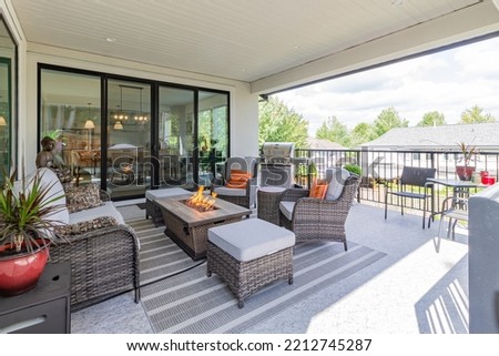 A luxurious spacious deck with stylish patio furniture with a fire pit table heater and  barbecue grill.