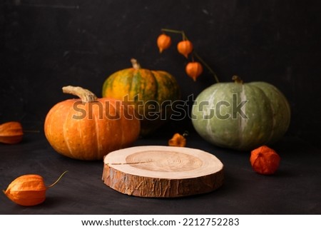 Halloween party concept. Wooden Podiums or pedestals for products display. with autumn orange physalis and pumpkins on a black background. Still life for the presentation. layout for natural cosmetics
