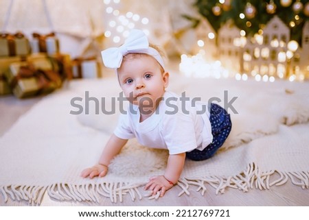 Adorable little girl playing with ornaments under decorated Christmas tree. High quality photo