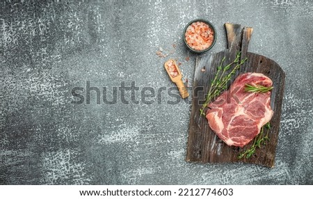 Raw meat pork steaks with seasoning on a wooden board. Long banner format.