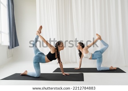 Two beautiful young girls are doing yoga in a snow-white room