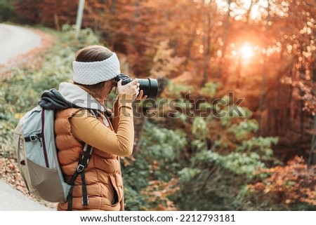 Young female photographer taking photos in the nature with her camera