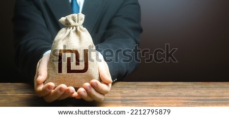 Businessman holds out israeli shekel money bag. Easy Money. Getting a grant. Mortgage, loan approval. Salary, benefits, profit. Attracting investments. Deposit savings. Cashback. Banking and crediting Royalty-Free Stock Photo #2212795879