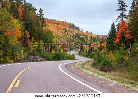 Curving road and colorful trees on hills near Caribou Lake in northern Minnesota during autumn