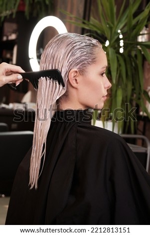 Young woman in a hairdressing salon dyes her hair blond and washing head. Royalty-Free Stock Photo #2212813151