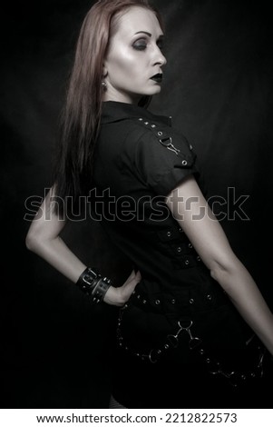 Pretty sad beautiful gothic girl posing over dark background