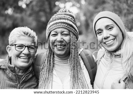 Portrait of multiracial female friends having fun during trekking day in mountain forest - Focus on right woman face - Black and white editing