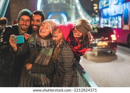 Young friends having fun doing selfie outdoor with London Tower Bridge in background - Soft focus on center girl face