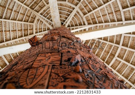 giant totem pole with thatched roof in sunny day