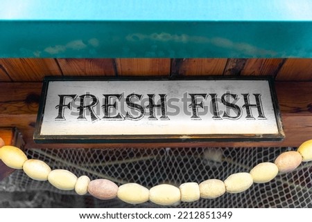 Fresh fish sign at entrance decorated with authentic net, buoys. Entrance to fish restaurant is designed to look like old fisherman tavern. Signboard fish from fishermen farm products fish market
