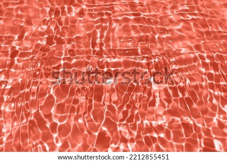 Defocus blurred transparent orange colored clear calm water surface texture with splash, bubble. Shining orange water ripple background. Surface of water in swimming pool. Orange bubble water shining.