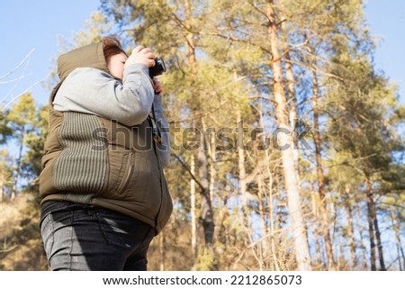 Side view photo of a photographer woman in winter cold sunny day making nature photo and spending good day outdoors.
