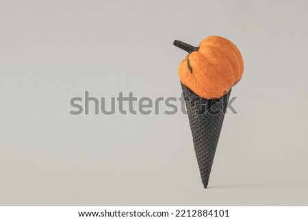 Ice cream made with black ice-cream cone and orange nature pumpkin. Halloween sweet dessert. Holiday minimal concept.